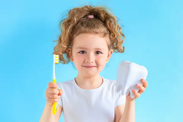 A young girl smiling with a toothbrush