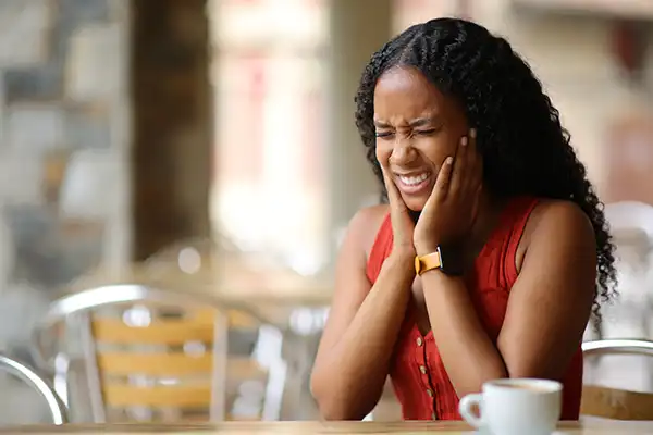 A young adult woman holding her jaw in pain