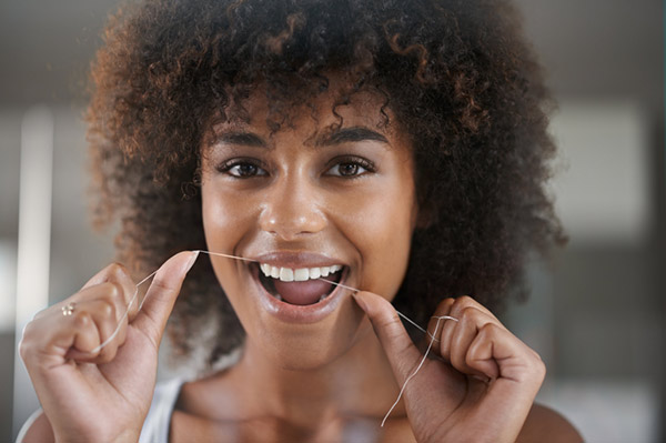 Woman smiling, while flossing.